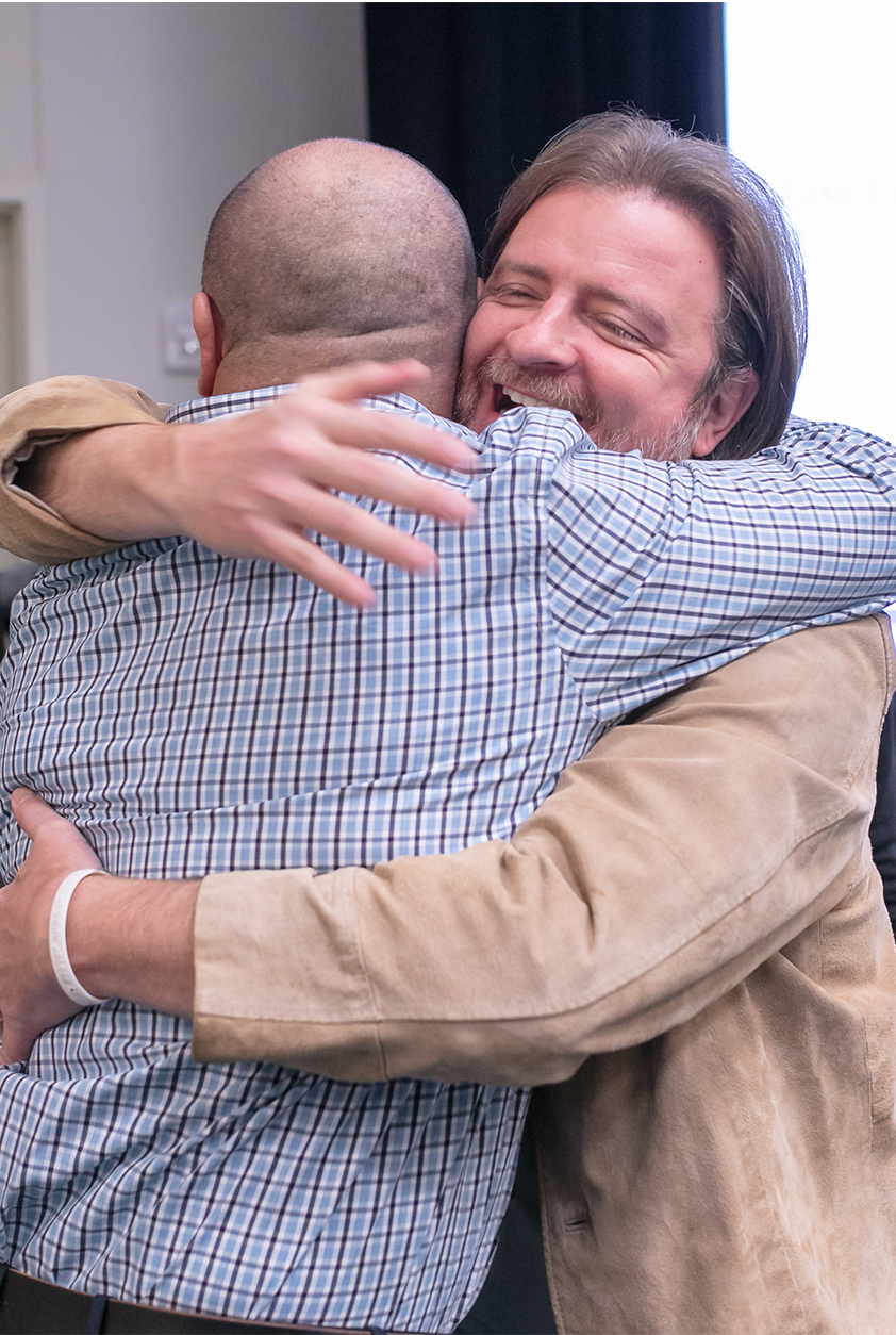 lean construction group two men hugging at an event