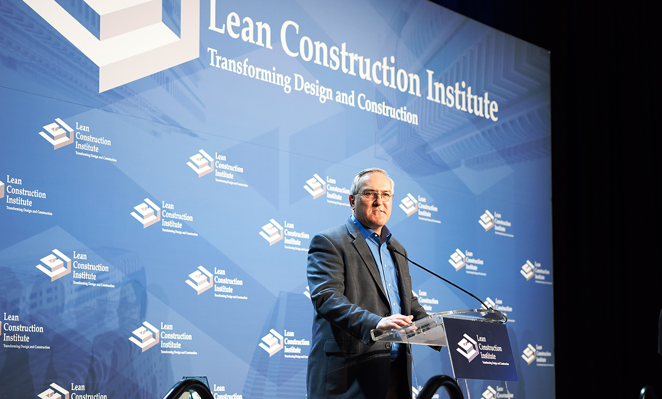 lean construction institute stage with man in black suit and blue shirt
