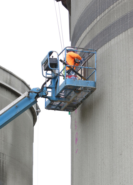 A construction worker on a lifted platform, performing work on the side of a building.